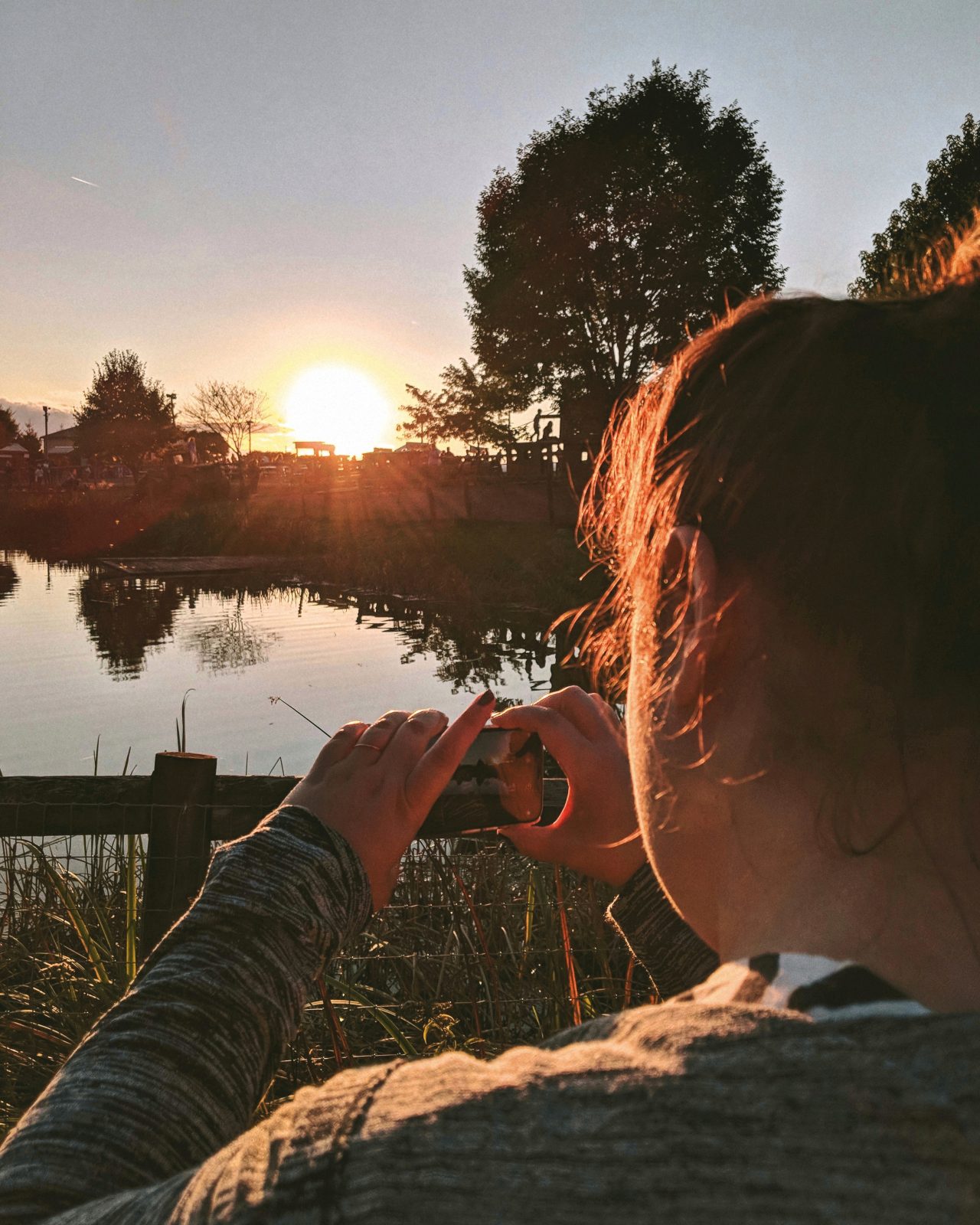 Eliza, taking a photo of a sunset over a pond.