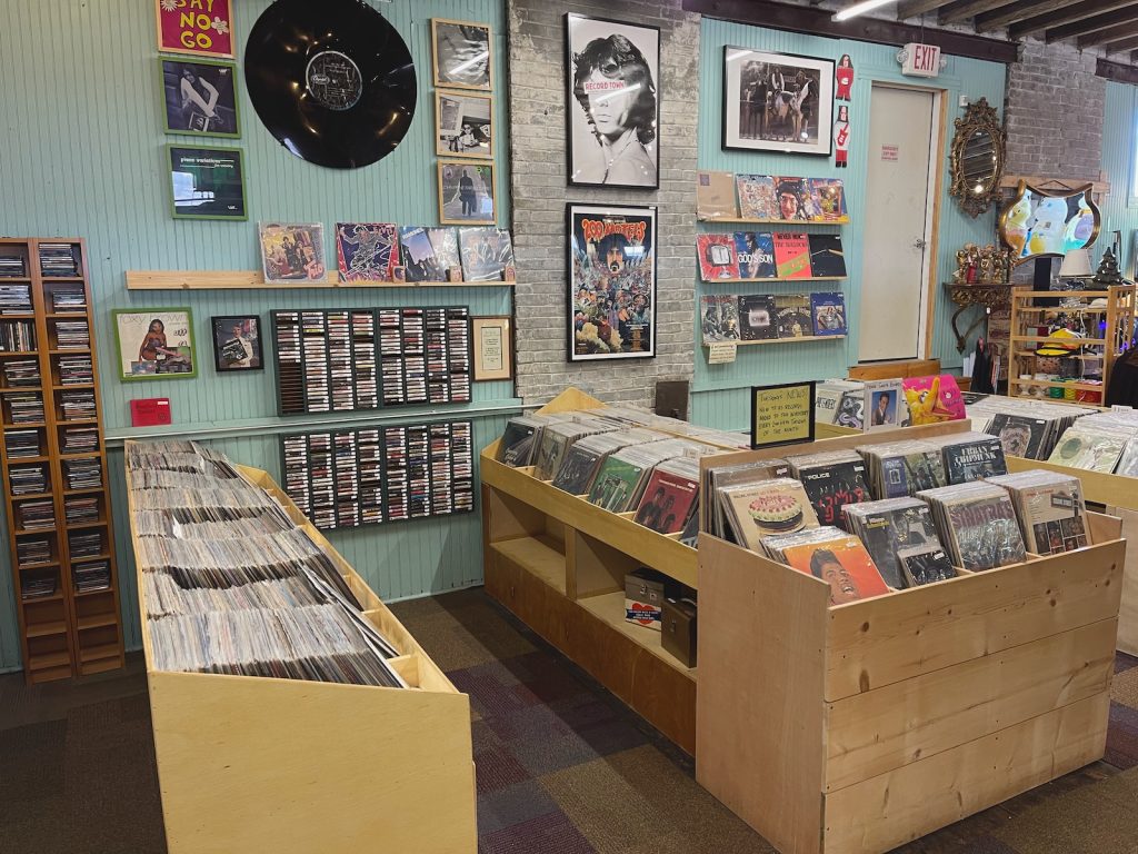 A few rows of records, posters and cassette tapes on the wall.
