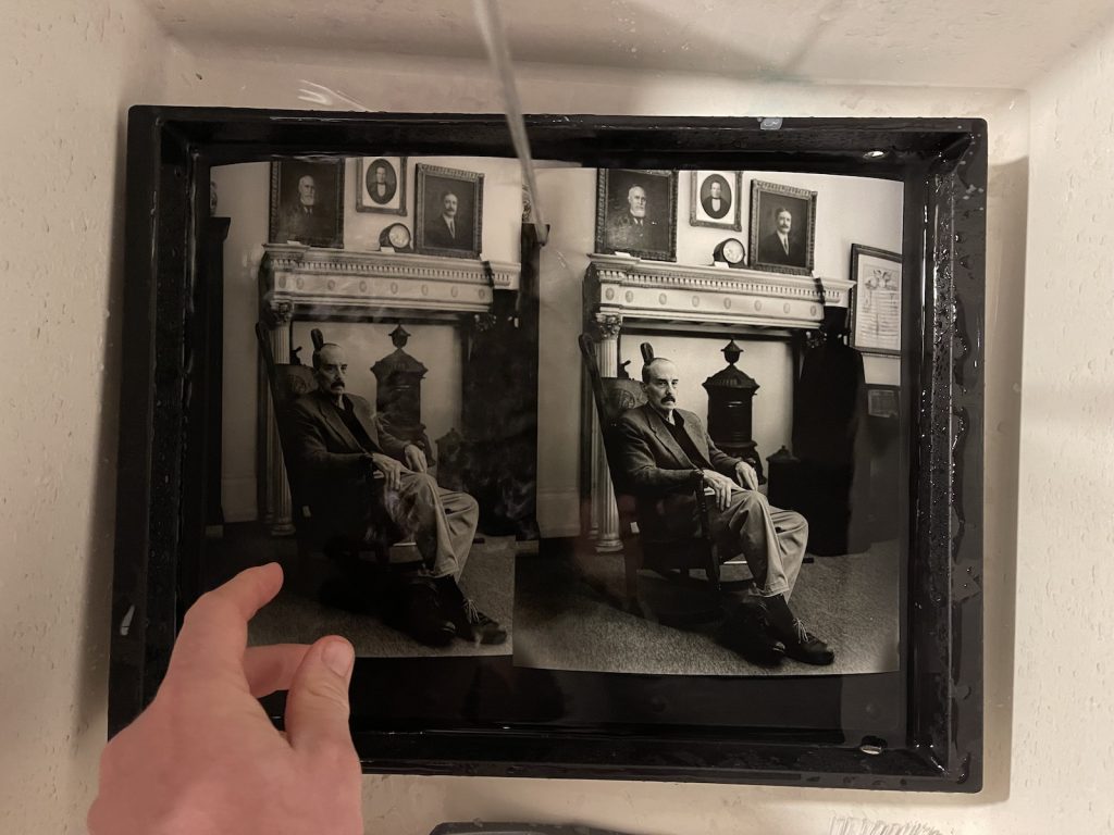 Two photos being washed in a sink, side by side.