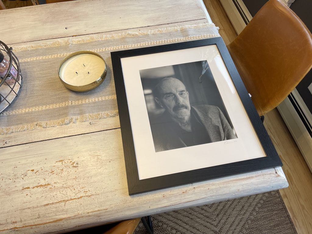 A framed photo resting on a dinner table.