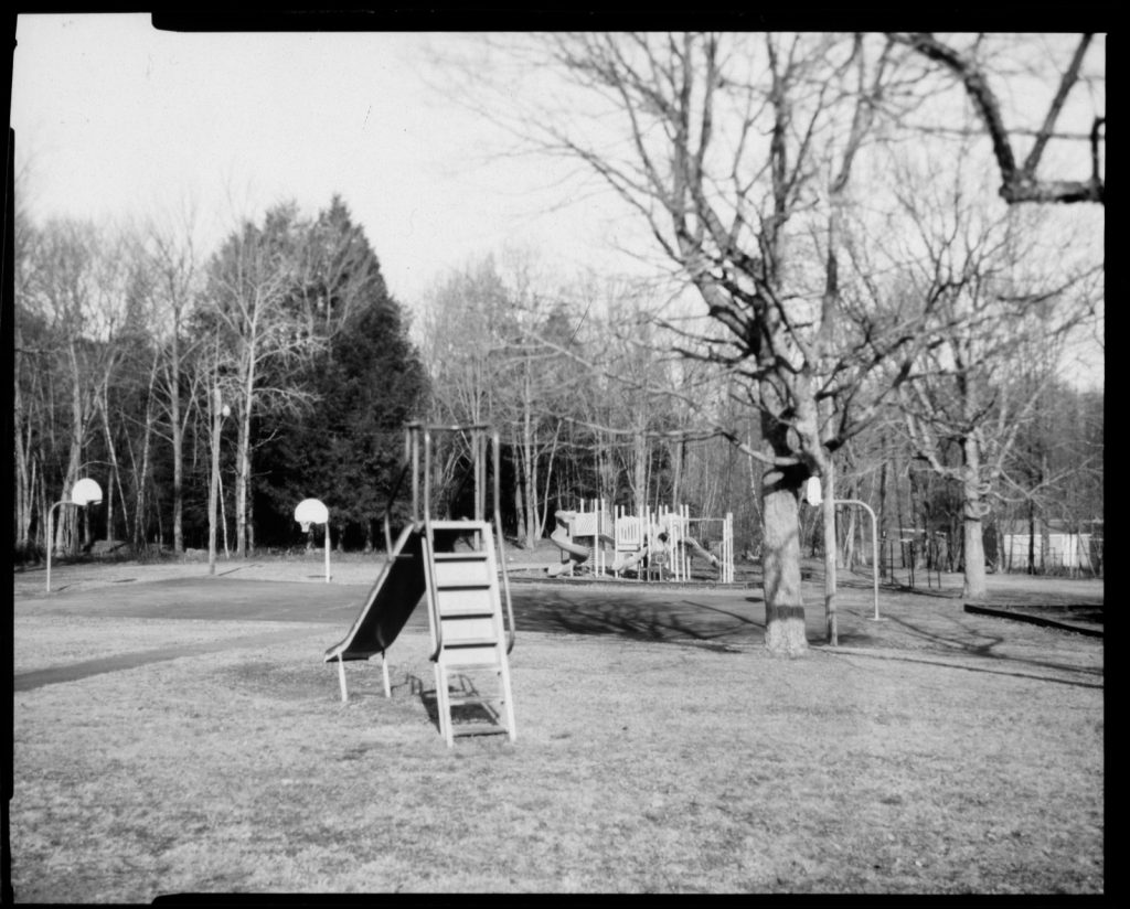 A black and white reversal scan of a paper negative of a school playground.
