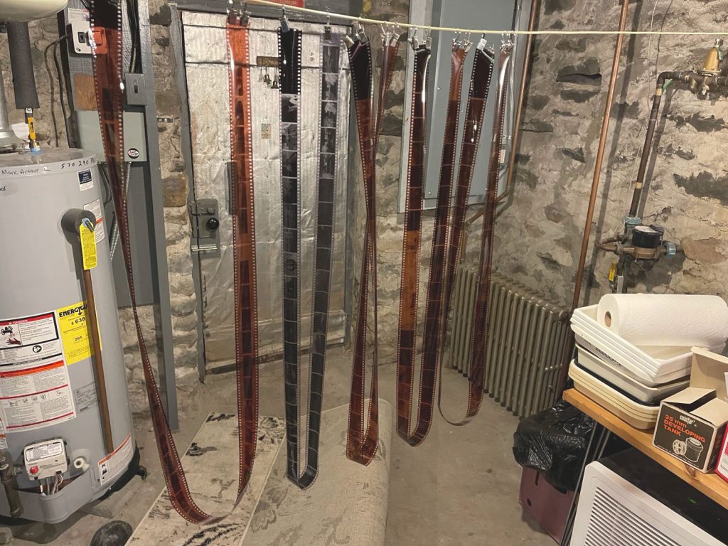 Strips of 35mm film negatives hang from a string in an old basement